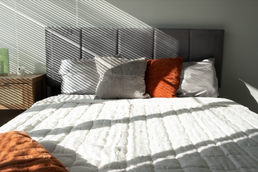 Bedroom staged by Design Domain with a grey channel headboard and rust accent pillows